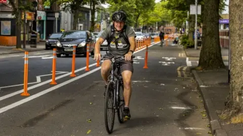 PA Media A man cycles in Belfast