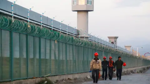 Reuters Workers walk by the perimeter fence of what is officially known as a vocational skills education centre in Dabancheng in Xinjiang Uighur Autonomous Region, China September 4, 2018.