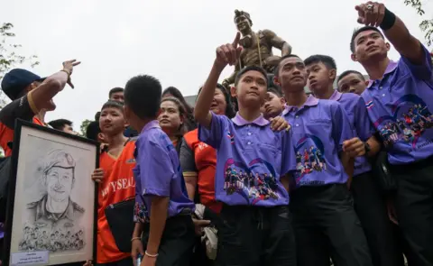 Members of the Wild Boars team next to a statue of Saman Gunan