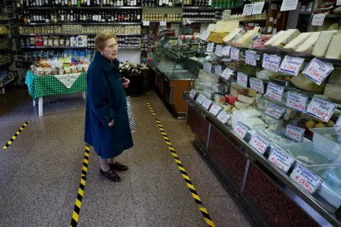 Reuters A lady waits to be served in a food shop