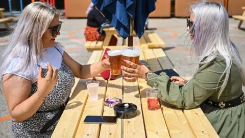Getty Images Two women with pints of beer sitting in a pub garden