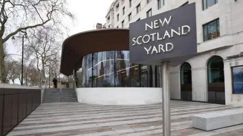 PA Media Glass-fronted entrance to New Scotland Yard, with the rotating sign in the foreground