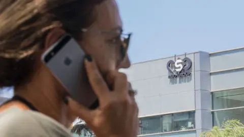 AFP An Israeli woman uses her iPhone in front of the building housing the Israeli NSO group, on August 28, 2016, in Herzliya, near Tel Aviv.