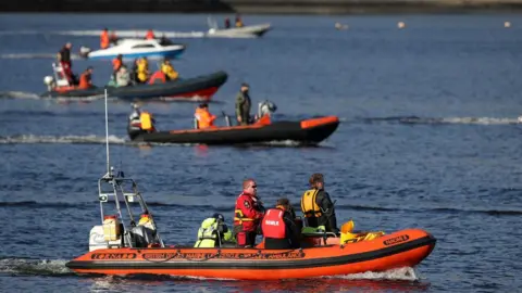 PA Media Boats try to corral the whales to the open sea