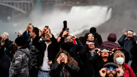 Visitors wear solar viewing glasses during an eclipse viewing event in Niagara Falls, Ontario, Canada