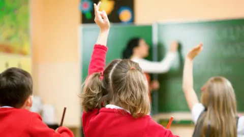 Getty Images Girl with hand up in class