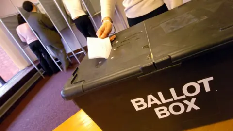 BBC Someone placing their vote in a ballot box