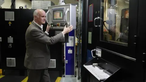 PA Media Martin Jennings at the coin striking machine