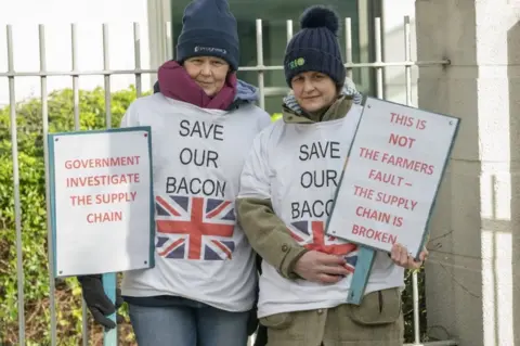 PA Media Pig farmers Vicky Scott (left) and Kate Moore during a demonstration outside the Department for Environment, Food Rural Affairs (Defra) office in York