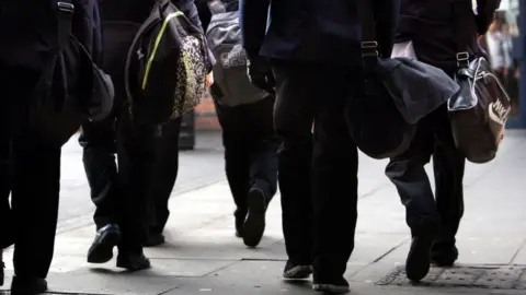 David Jones/PA Wire Schoolchildren walking with backpacks