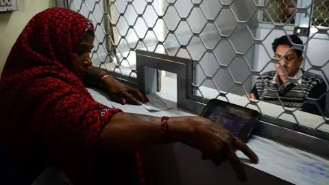 Getty Images A woman withdraws money at her bank