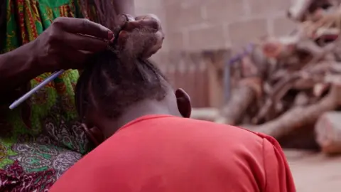 BBC/Simpa Samson Young girl having her hair braided.