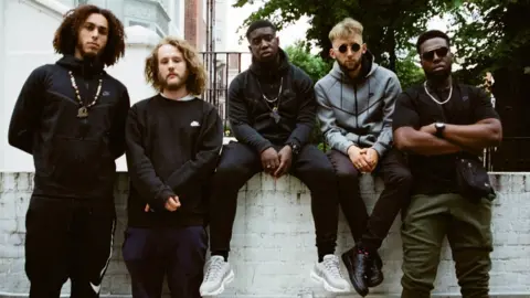 Love Supreme Festival The Ezra Collective sitting on a wall