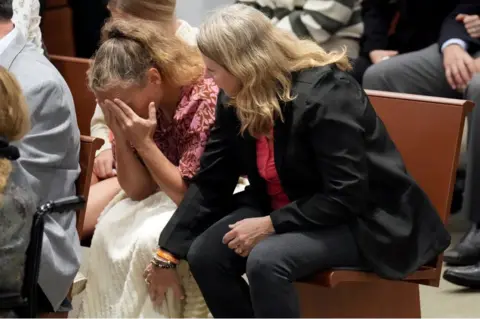 Pool/Getty Images Debbie Hixon reaches out to her sister-in-law, Natalie Hixon, as they hear that Debbie Hixon's husband's murderer will not receive the death penalty. Pictured at Broward County Courthouse on 13 October, 2022