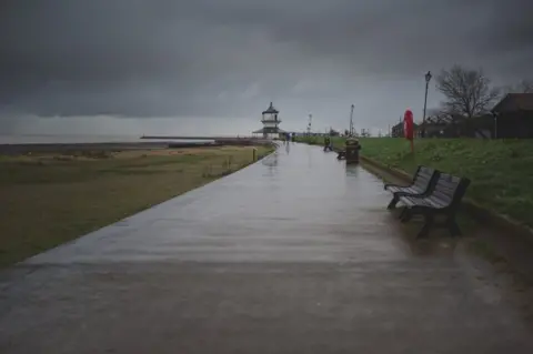 BBC A lone dog walker makes his way towards the Harwich Low Lighthouse