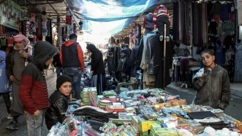 EPA Syrians walk in a popular market in Manbij, northern Syria (31 December 2018)