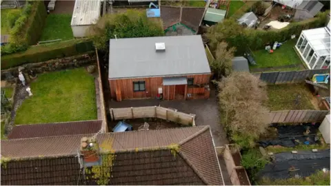 BBC John's new home, pictured from above. Photo shows grey roof and wooden exterior, surrounded by neighbours' gardens