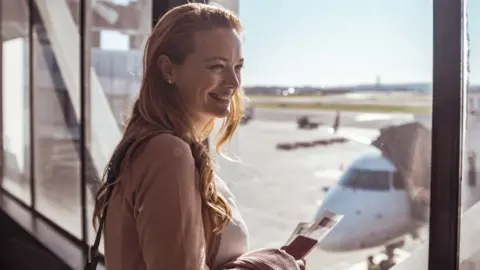 Getty Images Smiling woamn with passport