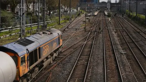 PA Media A wide view of the derailed train and empty fuel carriages behind it at West Ealing