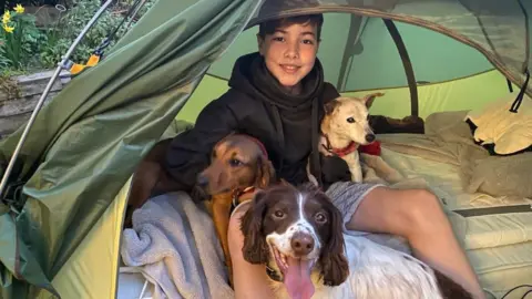 Family photo Ashley in his tent accompanied by his three dogs
