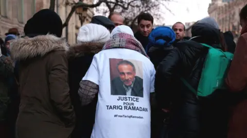 Getty Images A protester wears a shirt reading "Justice for Tariq Ramadan" during a gathering in support of Islamic scholar Tariq Ramadan, outside the courthouse of Paris, 22 February 2018