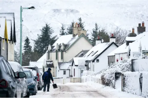 PA Media A man clears snow away in Leadhills, South Lanarkshire