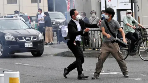 Asahi Shimbun/Reuters Police officer confronting gunman