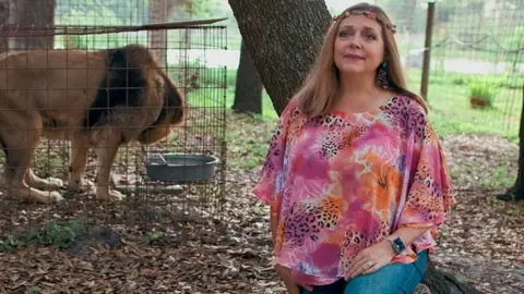 Netflix Woman in colourful shirt next to a lion cage