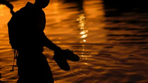 An asylum-seeking migrant crosses the Rio Bravo river, the border between the United States and Mexico, to request asylum in El Paso, Texas, U.S., as seen from Ciudad Juarez, Mexico December 21, 2022.