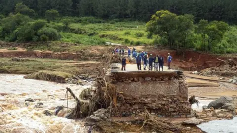 AFP Timber company workers stand stranded on a damaged road on 18 March 2019, at Charter Estate in Chimanimani, eastern Zimbabwe.
