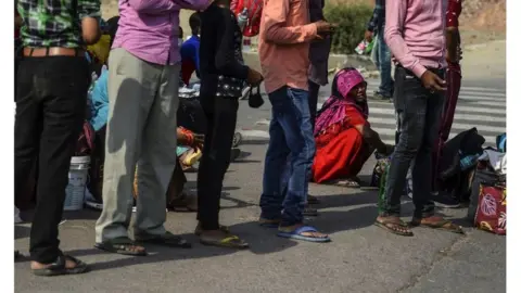 EPA Migrant workers with their families rest at a roadside on their journey back to their hometowns in Uttar Pradesh and Bihar states