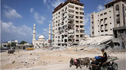 Getty Images Donkey pulls man on a cart past damaged buildings in Gaza (23/09/21)