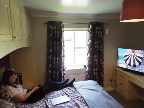 BBC Phoebe lying on her parents' bed, watching TV