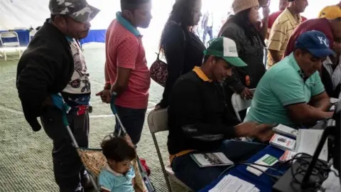 AFP Migrants queue to register at an employment fair near the US-Mexico border in Tijuana, Mexico, on November 19, 2018