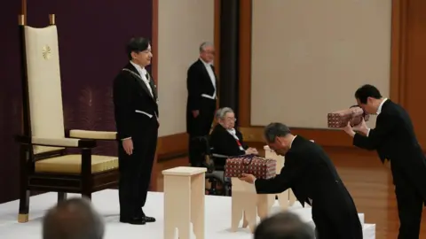 Reuters Japan's Emperor Naruhito, flanked by Prince Hitachi, attends a ritual called Kenji-to-Shokei-no-gi