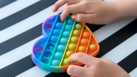 Getty Images Hands playing with a heart-shaped pop-it