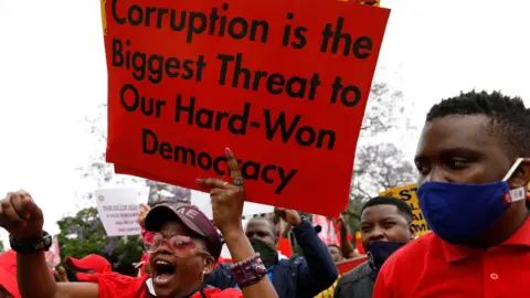 Getty Images Someone holds up a sign saying "Corruption is the biggest threat to our hard-won democracy" during a trade union strike, Pretoria, South Africa - 7 October 2020