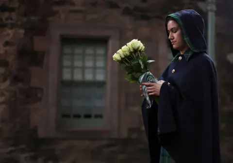 Carl Recine/Reuters A Warden of the Palace of Holyroodhouse holds flowers