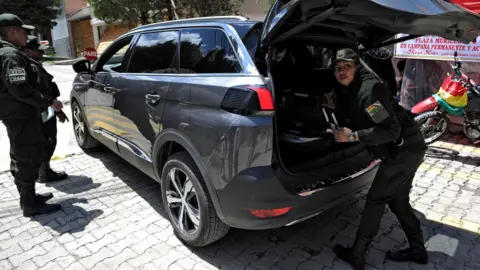 Getty Images Police officers check a vehicle outside La Rinconada gated community, where the Mexican embassy is located, in La Paz on December 30, 2019.