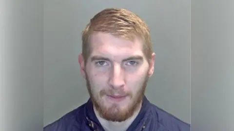 Suffolk Police Joshua Terry, he is white with brown hair and beard.