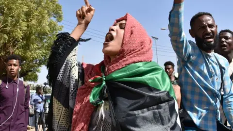 Getty Images Sudanese demonstrators carry placards and chant slogans as they protest outside the Foreign Ministry in the capital Khartoum on January 28, 2020.