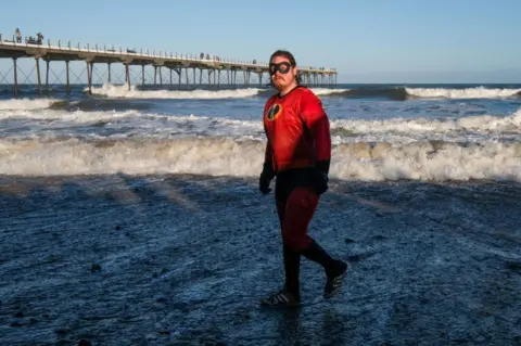 Ian Forsyth/Getty Images A swimmer in fancy dress leaves the chilly water of the North Sea after taking part in the New Year Day Dip in Saltburn