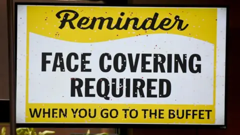 Getty Images A sign tells customers to wear masks