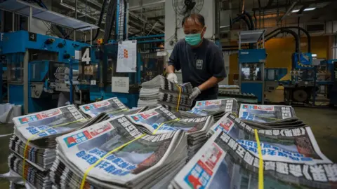 Getty Images An employee stacks freshly printed papers onto a pallet in the printing facility of the Apple Daily newspaper offices in Hong Kong