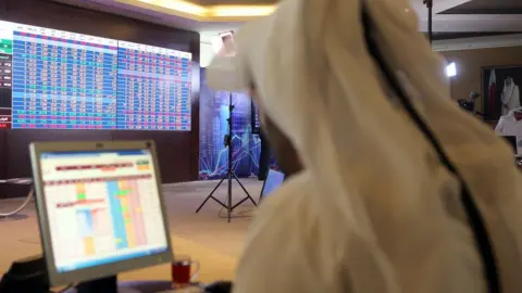 AFP File photo showing a Qatari trader following the stock market at the Qatari stock exchange in Doha (31 July 2017)