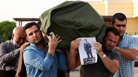 Getty Images Iraqi Kurdish men carry the coffin of a Kurdish migrant, who died in a lorry in Austria alongside other migrants in 2015