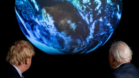 Getty Images Boris Johnson and David Attenborough looking at planet earth graphic