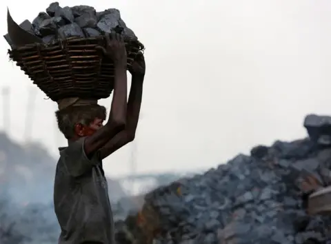 Getty Images An Indian worker carries a basket of coal collected at a mine in the state of Jharkhand.