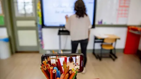 PA Media A teacher gives a class over her mobile phone