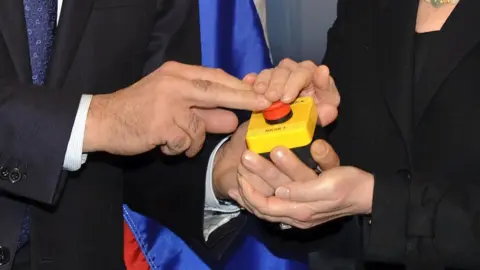 Getty Images The hands of US Secretary of State Hillary Clinton and Russian Foreign Minister Sergei Lavrov rest on a red button marked 'reset' in English and 'overload' in Russian